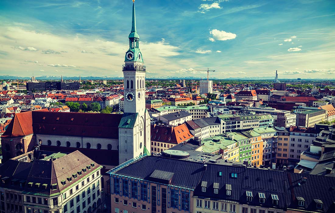 A view of the city from above shows buildings, a clock tower and a green roof.