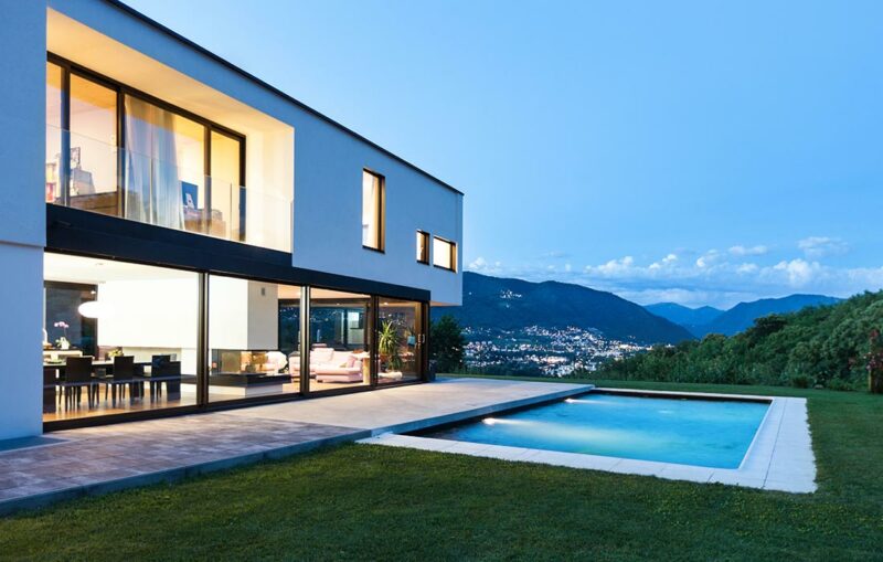 A large pool in front of a house with a mountain view.